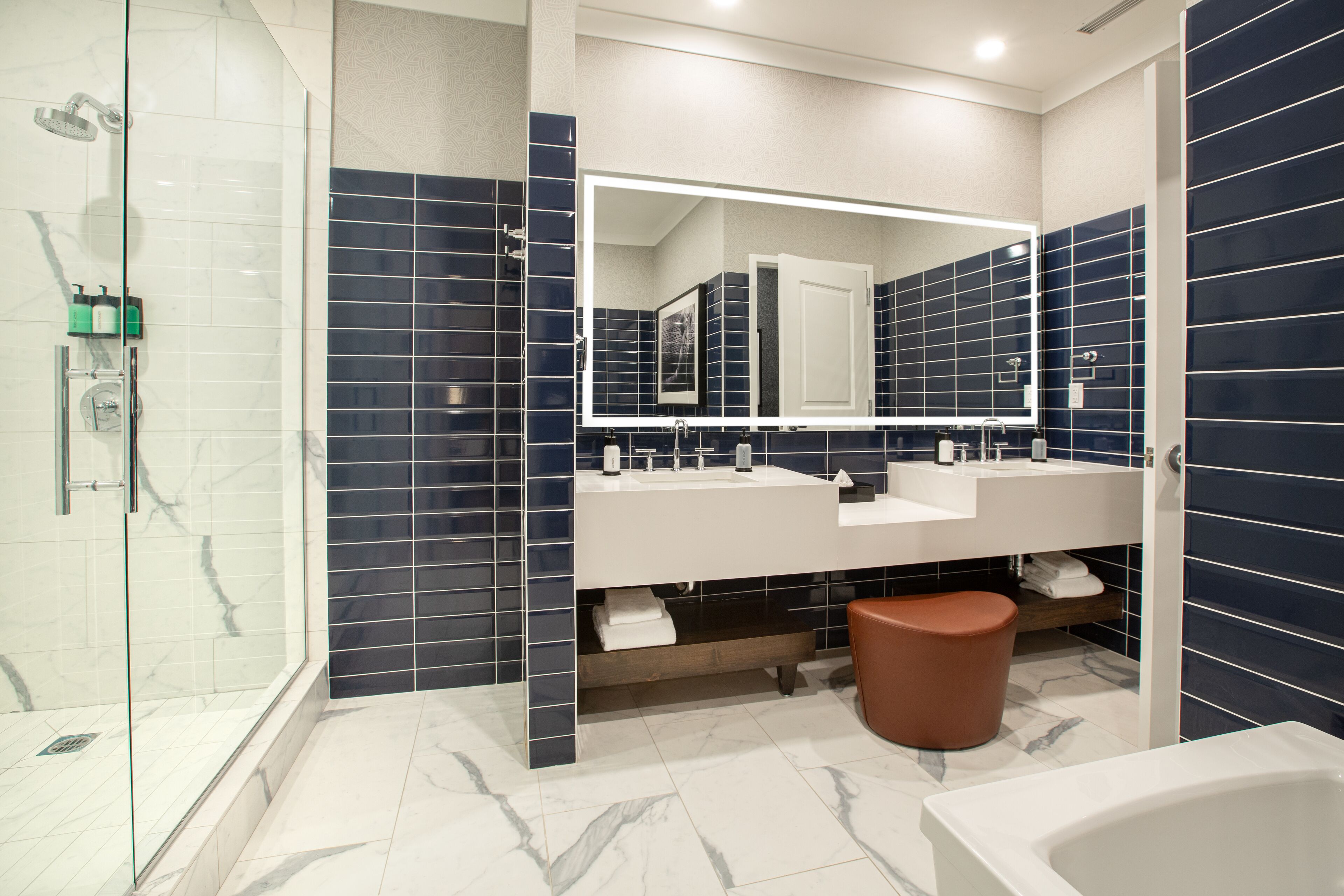 Une salle de bain moderne dotée d’une douche à parois de verre, de deux vasques et d’un grand miroir.