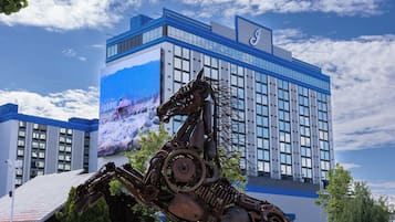 Un edificio con un gran mural en una fachada y una escultura de metal en primer plano.