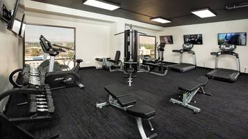 A gym with various exercise equipment, including treadmills, a bench press, and weight machines.