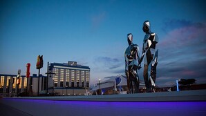 A modern building with a prominent 'J' logo, surrounded by abstract sculptures and a clear sky at dusk. - J Resort (Reno)