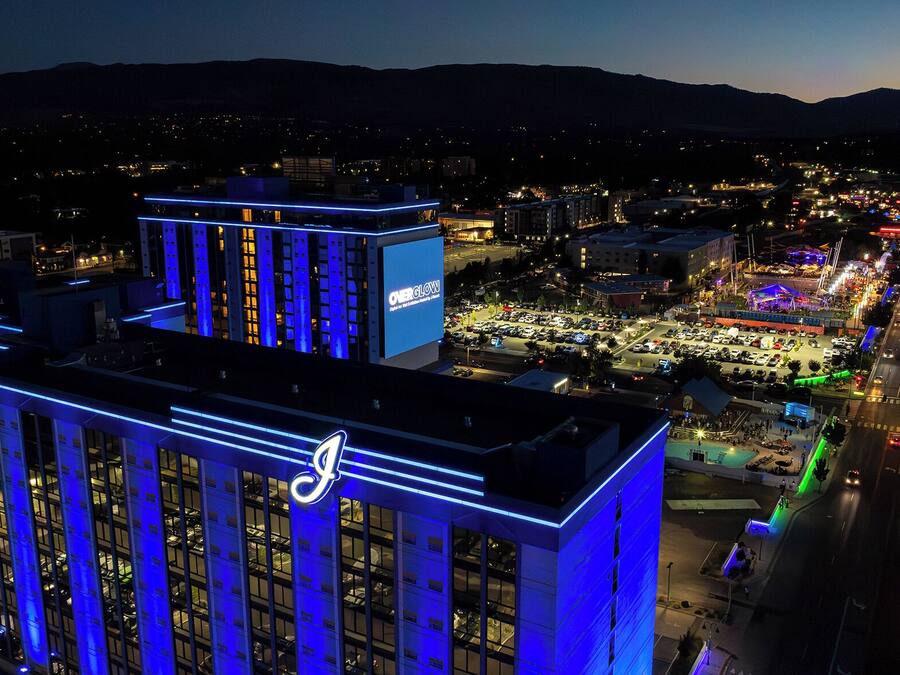 Un hôtel de grande hauteur, agrémenté de lignes bleues illuminées et d’un grand panneau publicitaire faisant la promotion de « OverGlow ».