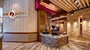 A reception area with a wooden reception desk, a stone wall, and a logo on the wall. - J Resort (Reno)