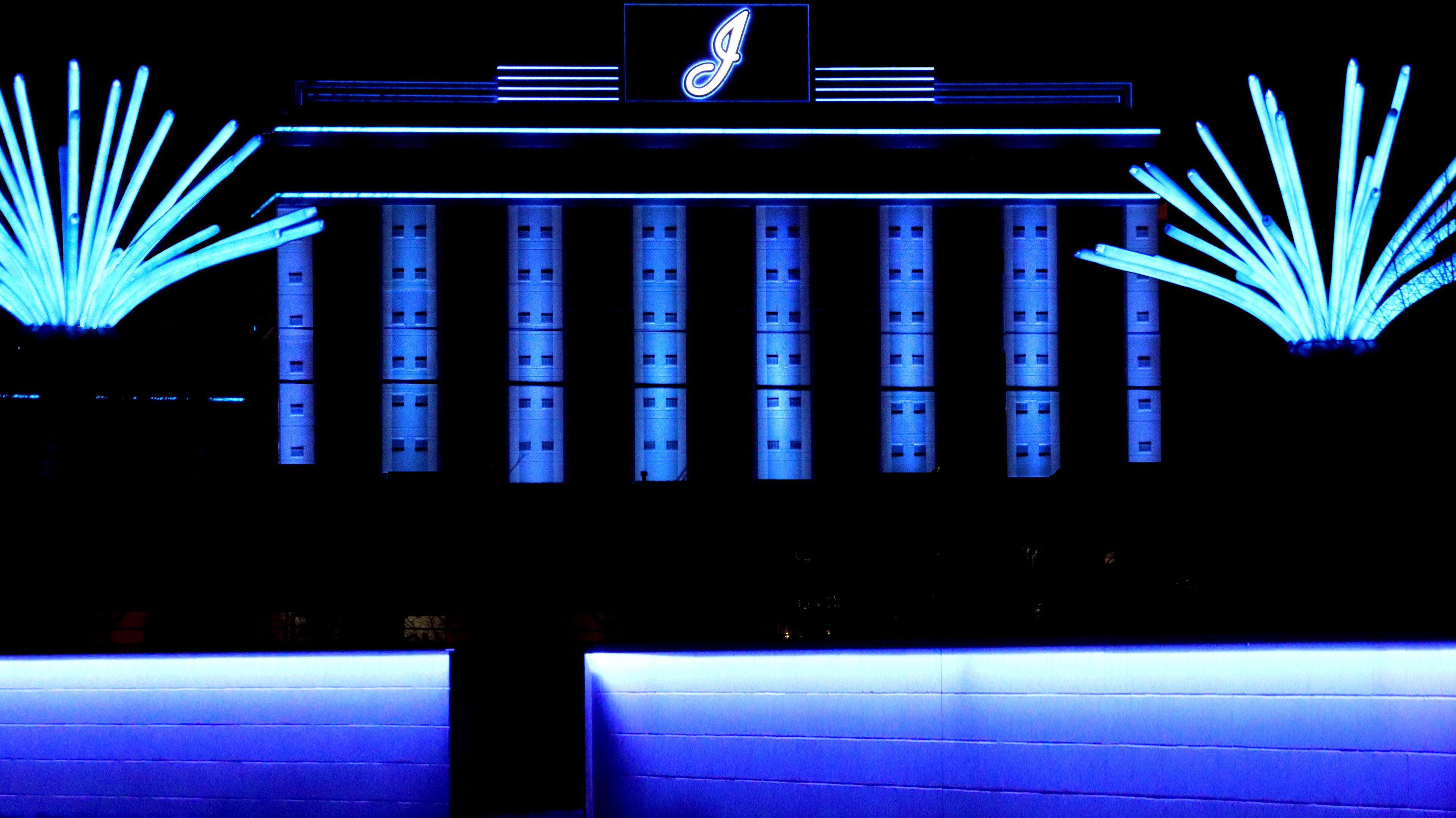A building facade with illuminated vertical columns and a central logo.