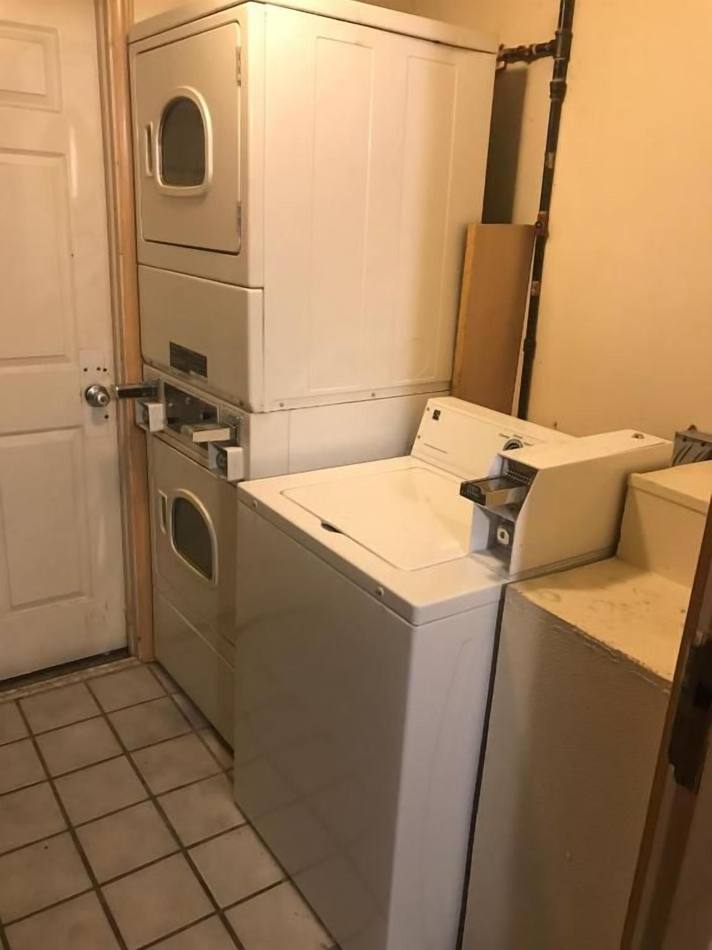 A compact laundry area with a washer and dryer, a small sink, and a door leading to another room.