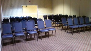 Un salón de conferencias con filas de sillas y piso alfombrado.