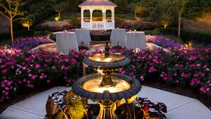 A garden with a central fountain, surrounded by tables and chairs, and a gazebo in the background. - Ann Arbor Regent Hotel & Suites (Ann Arbor)