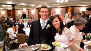 Een formeel evenement met gasten die aan tafels zitten, een buffet en een man in pak en das.