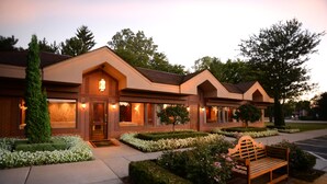 A modern building with a brick facade, large windows, and a well-maintained garden with a bench. - Ann Arbor Regent Hotel & Suites (Ann Arbor)