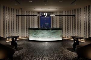 A modern interior with a central table and two chairs, a cityscape view through a window, and a sign reading "Table 9 Tokyo Dining & Bar".