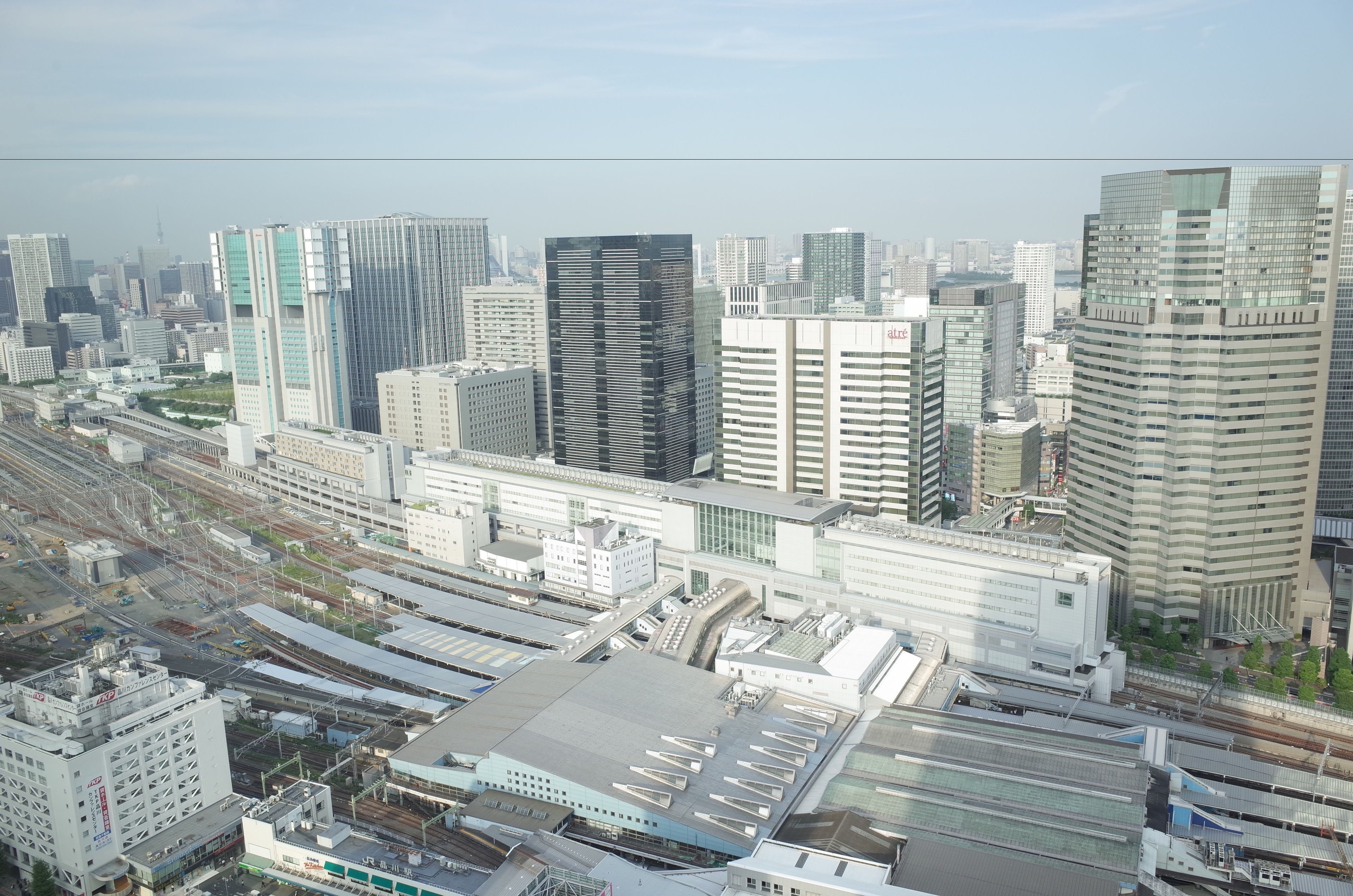 A high-rise urban area with modern buildings, a train station, and a large parking structure.
