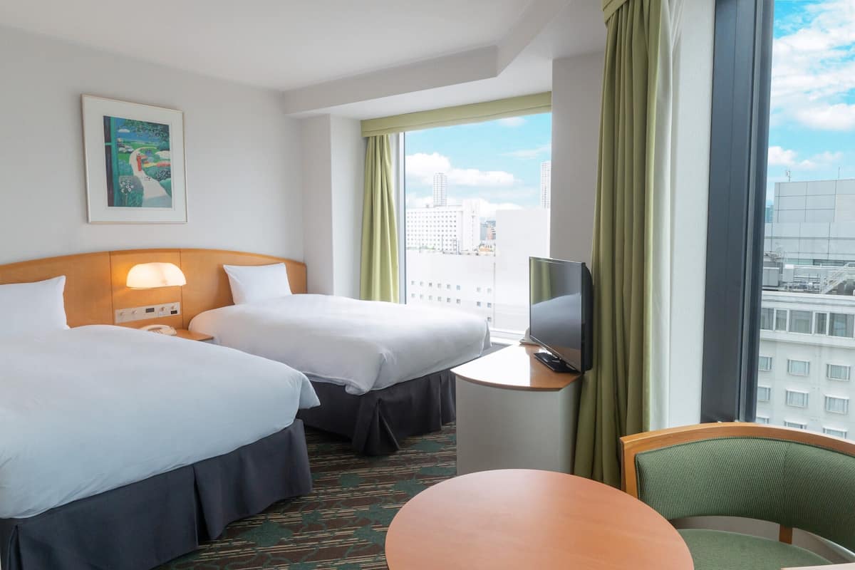 A hotel room with two beds, a TV, a desk, and a chair.