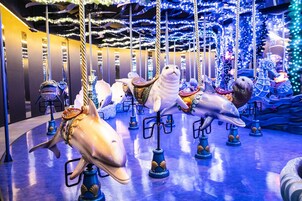 A carousel with various animal figures, including a shark, seal, and dolphin, set against a backdrop of blue lighting and decorative elements.