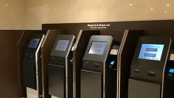 A row of check-in and check-out kiosks in a hotel lobby.