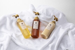 Three bottles of body care products on a white towel.
