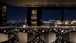 A bar with a city view, modern chairs, and a shelf with bottles. - Shinagawa Prince Hotel (Tokyo)