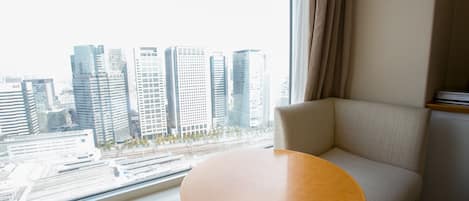 A hotel room with a large window offering a view of a cityscape.