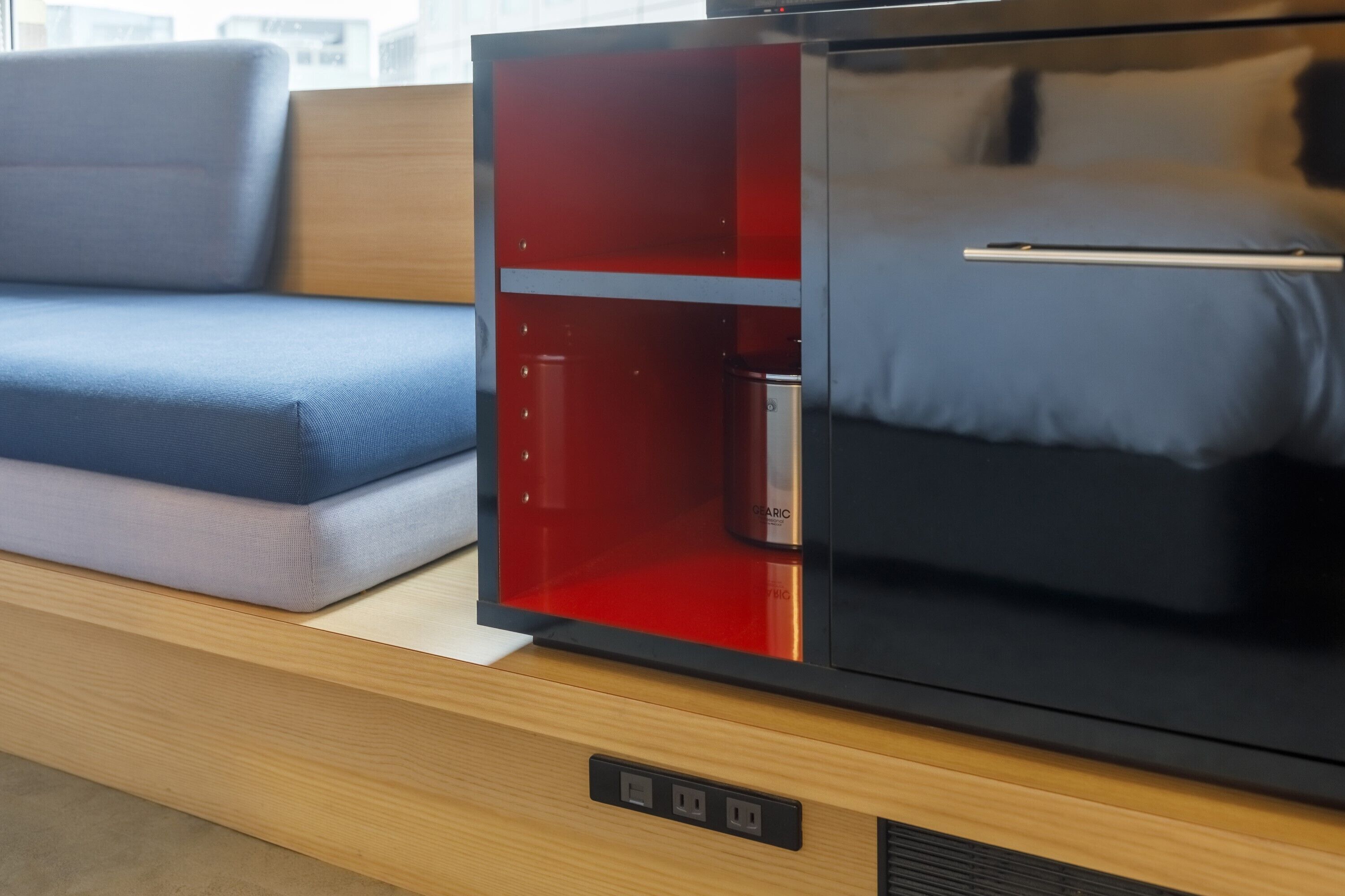 Un espacio habitable moderno con un sofá, un armario rojo y un mueble multimedia negro.