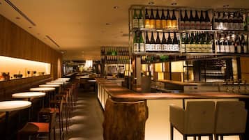 A bar area with multiple tables and chairs, shelves with bottles, and a wooden bar counter.