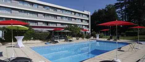 Una piscina al aire libre de temporada, sombrillas, tumbonas