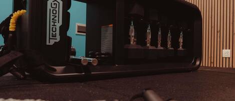 Un gimnasio con equipo de ejercicio, un estante con botellas en la pared y una pared azul de fondo.