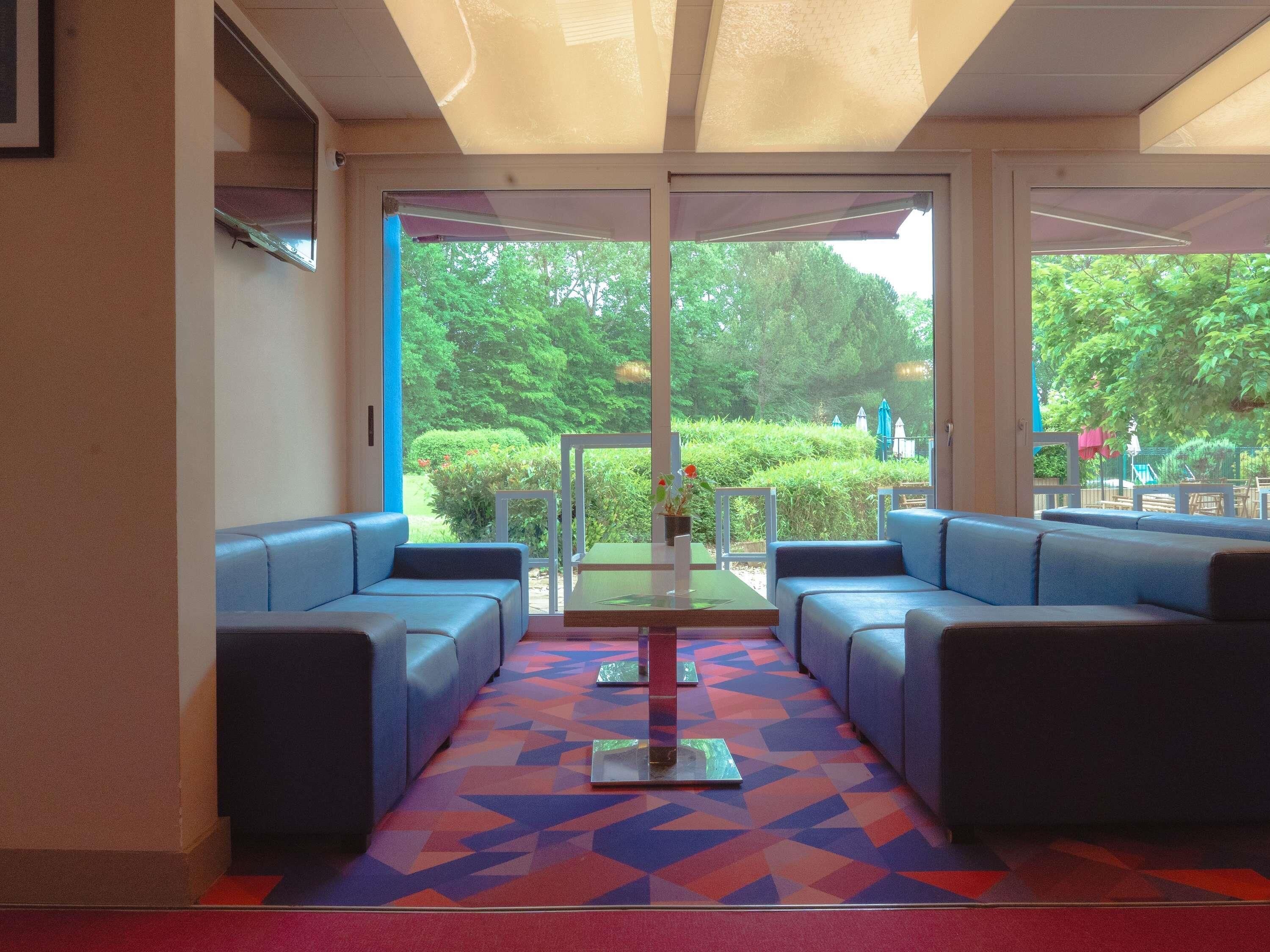 Un hall con un sofá azul, una mesa de vidrio y una alfombra estampada.