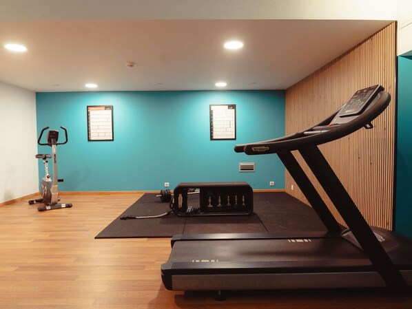 A gym with a treadmill, stationary bike, and weight bench.