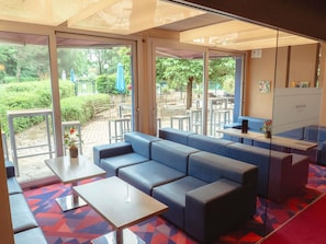 A modern hotel lobby with a blue sofa, a small table, and a glass partition.