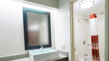 A bathroom with a white sink, a mirror, a shower with a curtain, and a toilet.
