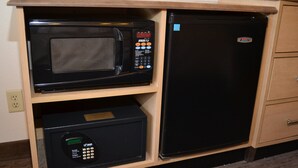 Una cocina compacta con un microondas en un estante superior y un refrigerador debajo.
