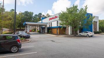 A hotel with a 'Welcome' sign, a covered parking area, and a building with a blue and white facade.