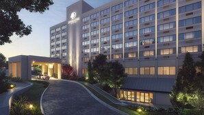 Un hôtel moderne, avec une enseigne bien visible, une entrée abritée et une allée bordée de verdure.