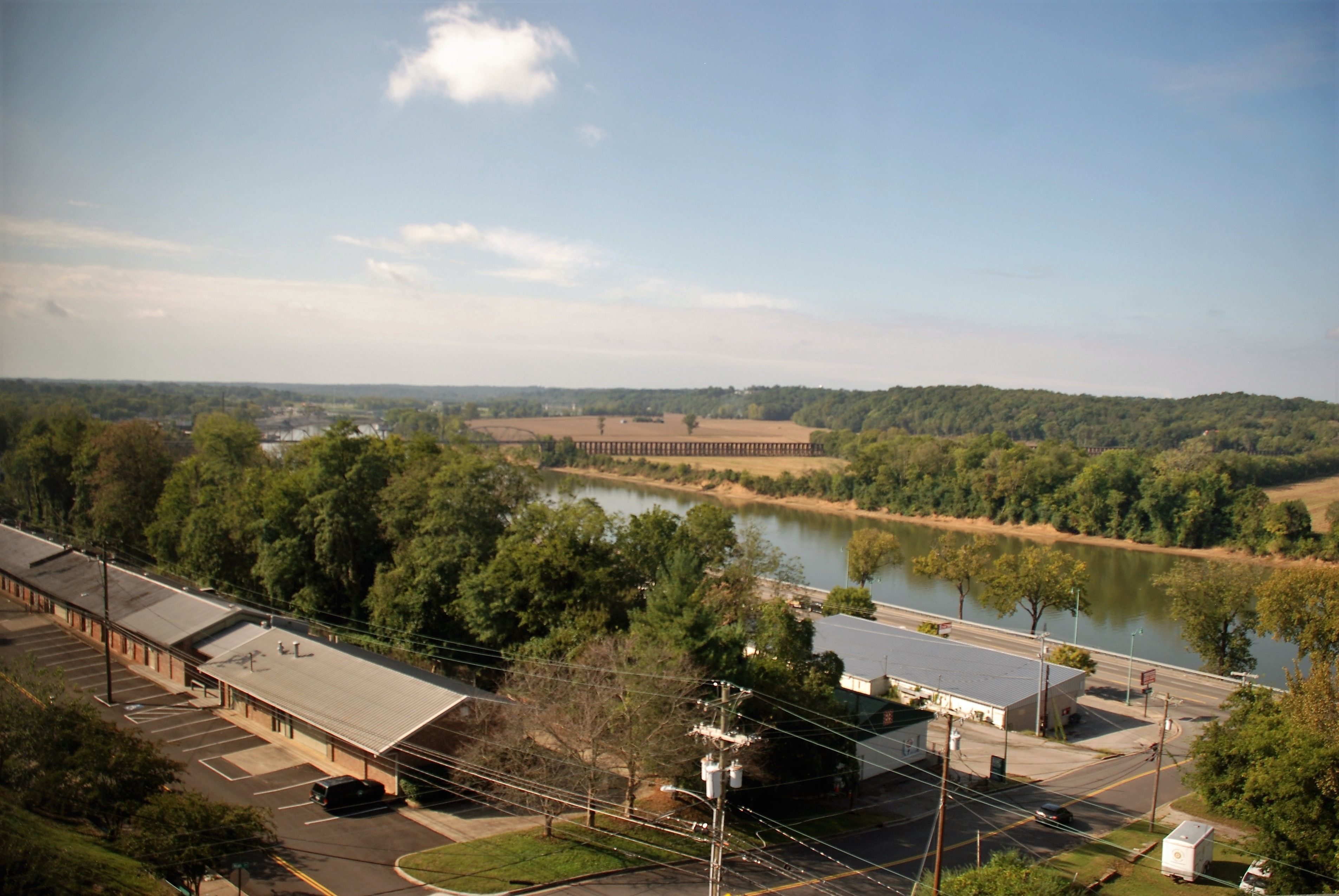 A parking lot, a building with a flat roof, and a river in the background.