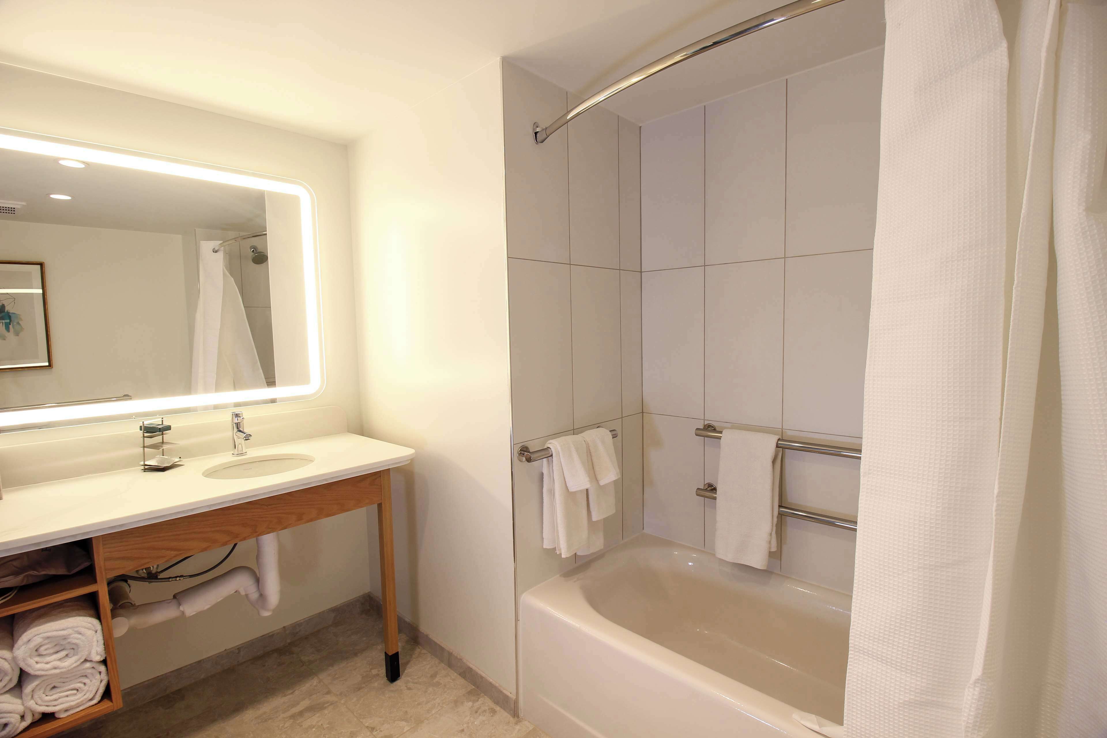 A modern bathroom with a large bathtub, a vanity with a mirror, and a shower area.