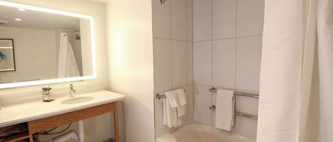 Un baño moderno con una bañera grande, un tocador con espejo y una zona de ducha.