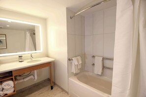 A modern bathroom with a large bathtub, a vanity with a mirror, and a shower area.