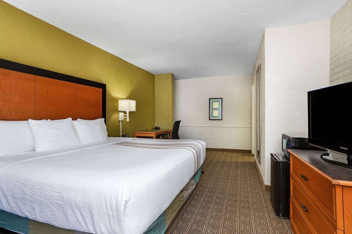 Una habitación de hotel con una cama grande, un escritorio, una silla, un televisor y una mesita.