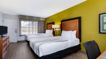 A hotel room with two beds, a TV, a desk, and a chair.