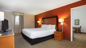 A hotel room with a large bed, bedside lamps, a desk with a television, and a chair.