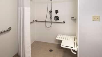 Un baño con ducha, barras de apoyo, inodoro blanco y un perchero para toallas.