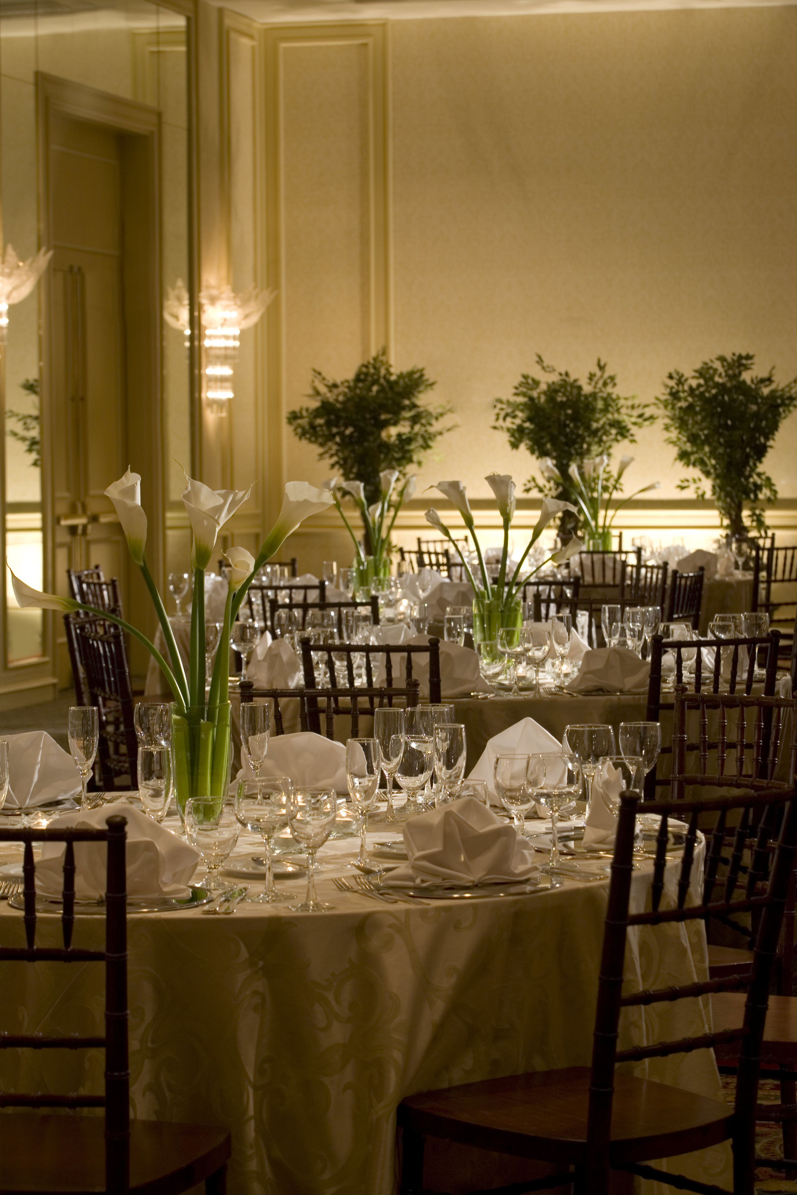 Un comedor elegante con mesas dispuestas para una comida, con manteles blancos, cristalería y centros de mesa florales.