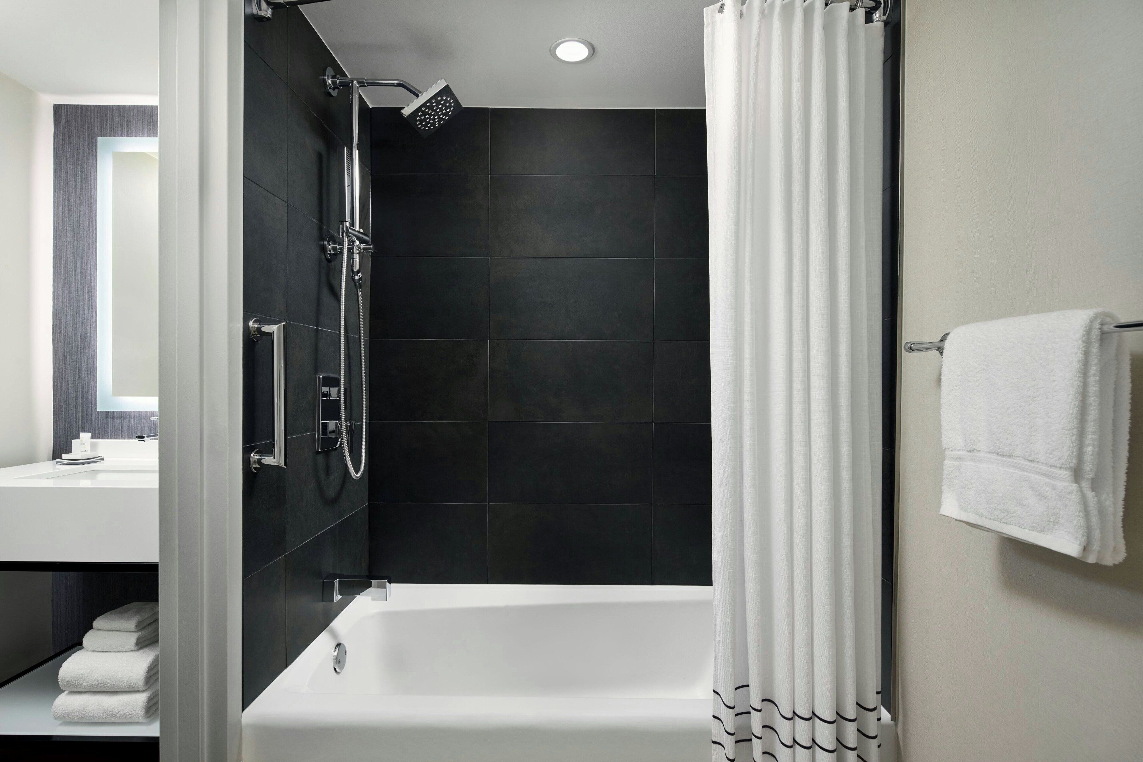 A modern bathroom with a shower, a bathtub, and a vanity with a mirror.