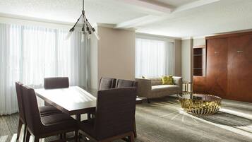 A hotel room with a dining area, a sofa, a coffee table, and a wardrobe.