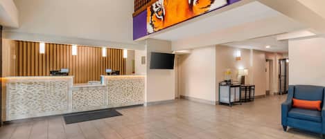 Vestíbulo de hotel con mostrador de recepción, un gran mural de tigre, televisor y zona de estar con un sofá azul.