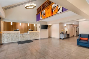 Vestíbulo de hotel con mostrador de recepción, un gran mural de tigre, televisor y zona de estar con un sofá azul.