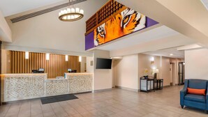 A hotel lobby with a reception desk, a large tiger mural, a TV, and a seating area with a blue sofa.