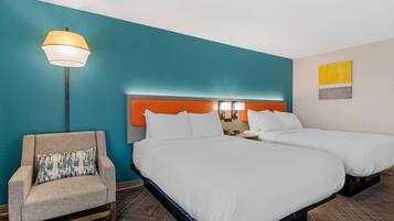 A hotel room with two beds, a sofa, a lamp, and a wall with a painting.