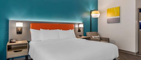 A hotel room with a bed, nightstands, a lamp, and a painting on the wall.