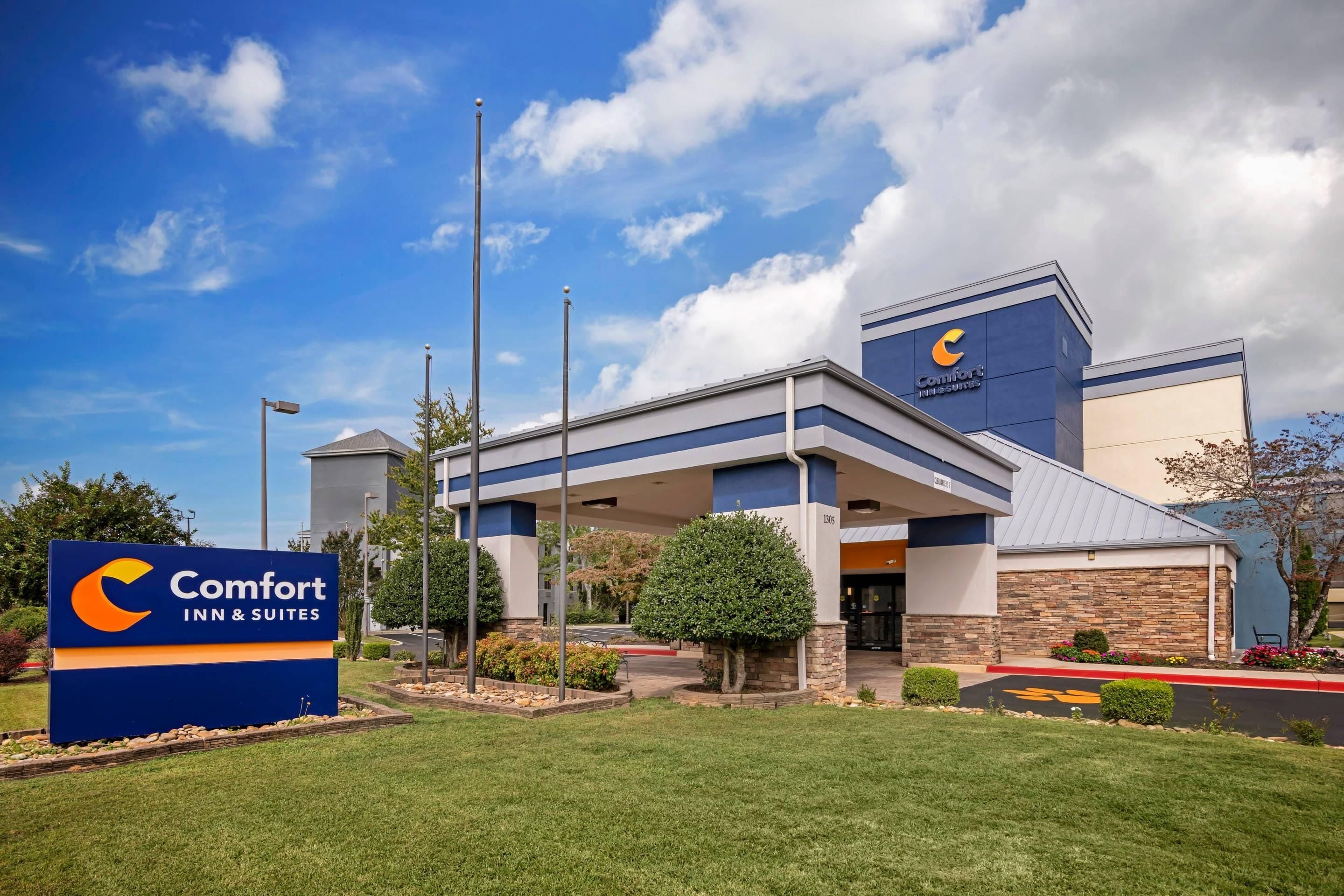 A Comfort Inn & Suites hotel with a clear sky, a well-maintained lawn, and a parking lot.