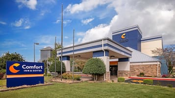 A Comfort Inn & Suites hotel with a clear sky, a well-maintained lawn, and a parking lot.