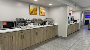 A modern kitchen with a microwave, toaster, and coffee maker. There are white bowls and a coffee station.